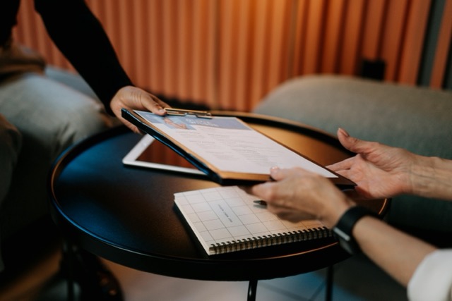 person in black long sleeve shirt writing on white pape learning how to write cv